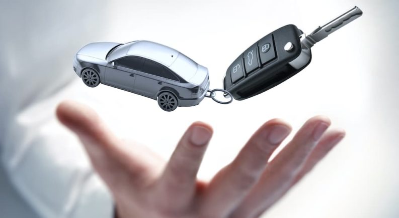 A hand is shown tossing a car key after searching 'sell my car.'