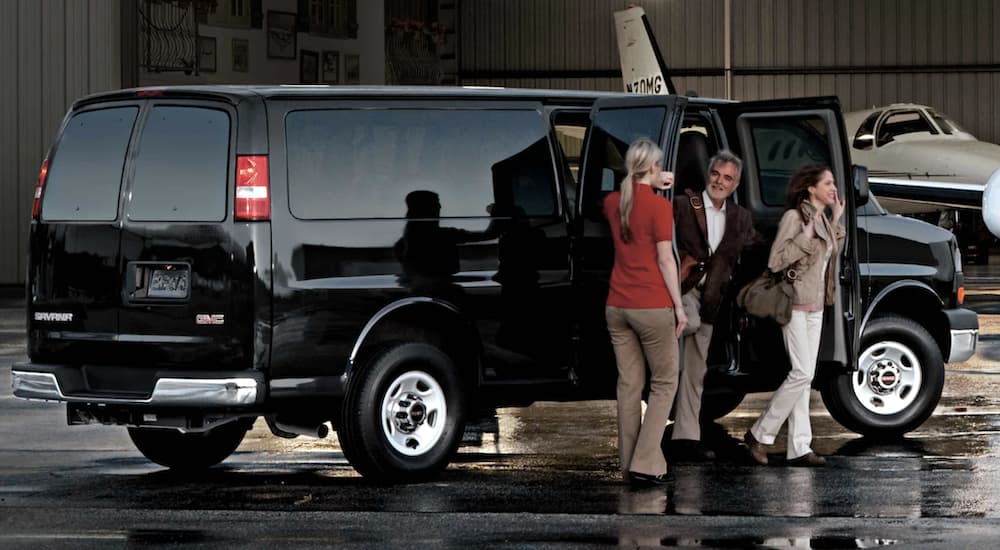 A black 2021 GMC Savana is shown from the side parked as passengers leave the van.
