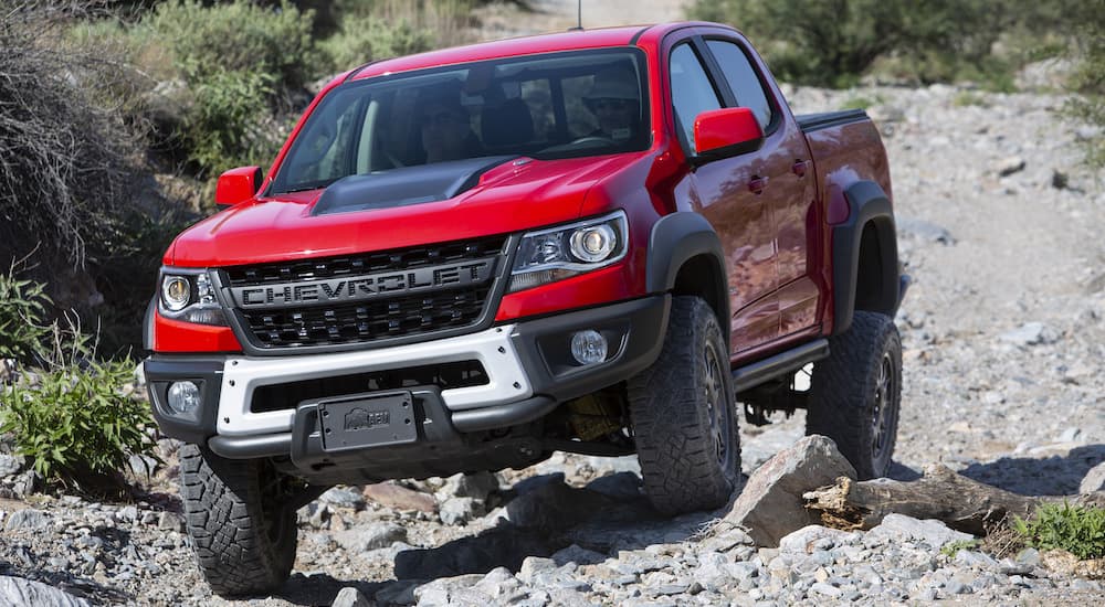 A red 2019 Chevy Colorado Zr2 Bison is shown from the front crawling over rocks after leaving a used Chevy dealer.