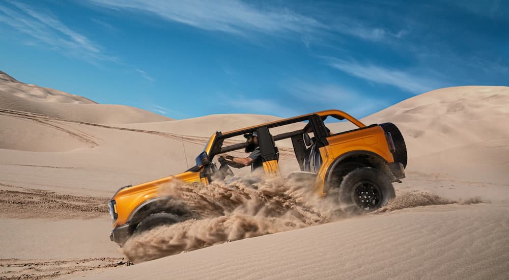 A yellow 2021 Ford Bronco with the Sasquatch package is shown from the side in a desert.
