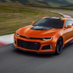 An orange 2022 Chevy Camaro ZL1 is shown driving around a race track.
