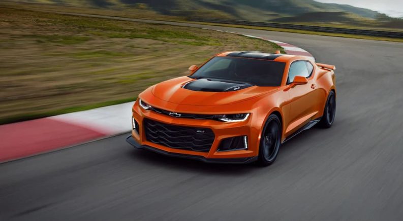 An orange 2022 Chevy Camaro ZL1 is shown driving around a race track.