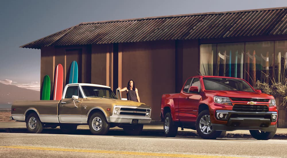 A red 2022 Chevy Colorado and a tan 1968 C20 are show parked outside a surf shop.