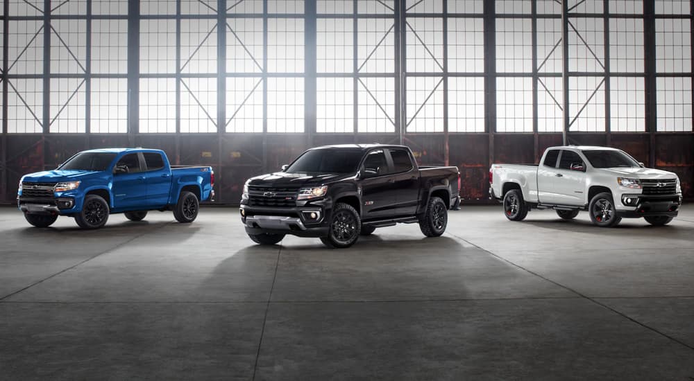 A blue, a black, and a white 2022 Chevy Colorado are shown parked in a warehouse.