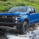 A blue 2022 Chevy Silverado 1500 ZR2 is shown from the front driving through a river.