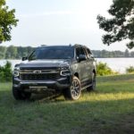A grey 2022 Chevy Suburban Z71 is shown parked near a lake.