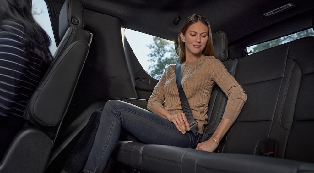 A woman is shown buckling into the backseat of a 2022 Chevy Tahoe.