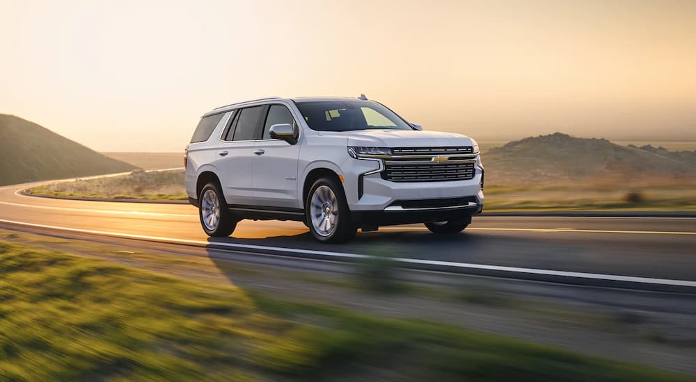 A white 2022 Chevy Tahoe Premier is shown driving down an open highway.