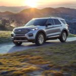 A silver 2022 Ford Explorer is shown driving on a road in the mountains.