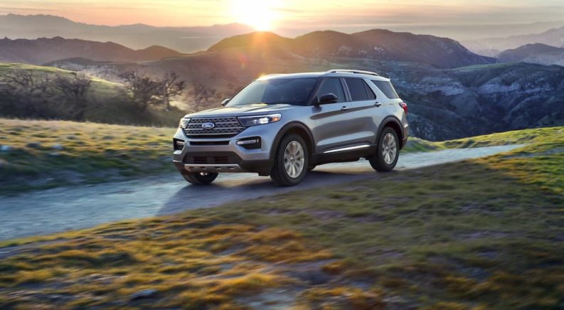 A silver 2022 Ford Explorer is shown driving on a road in the mountains.