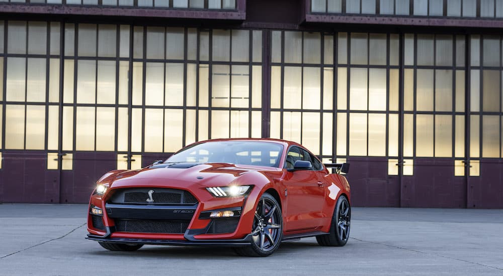 A red 2022 Ford Mustang GT 500 is shown parked on an empty lot.