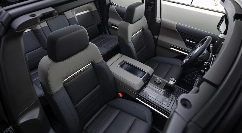The black and gray interior of a 2022 GMC Hummer EV Pickup shows the front seats and center console.