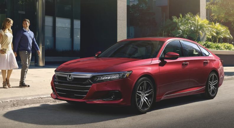 A red 2022 Honda Accord Hybrid Touring is shown from the side parked on a city street.