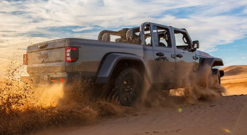 A silver 2022 Jeep Gladiator Mojave is shown from a low angle off-roading in a desert.