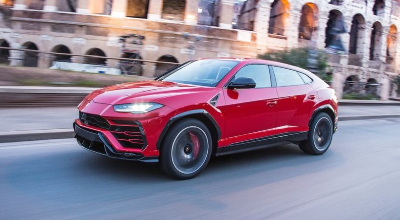 A red 2022 Lamborghini Urus is shown from the side while driving.