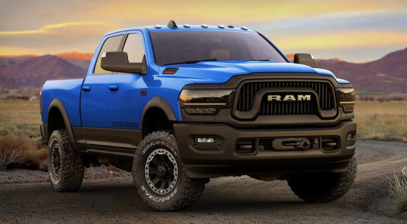 A blue 2022 Ram 2500 Power Wagon is shown from the front parked in a field at sunset.