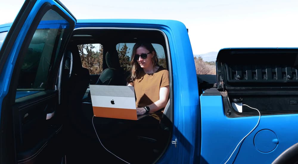 A person is shown sitting inside of a blue 2022 Ram 2500 Power Wagon while charging their computer.