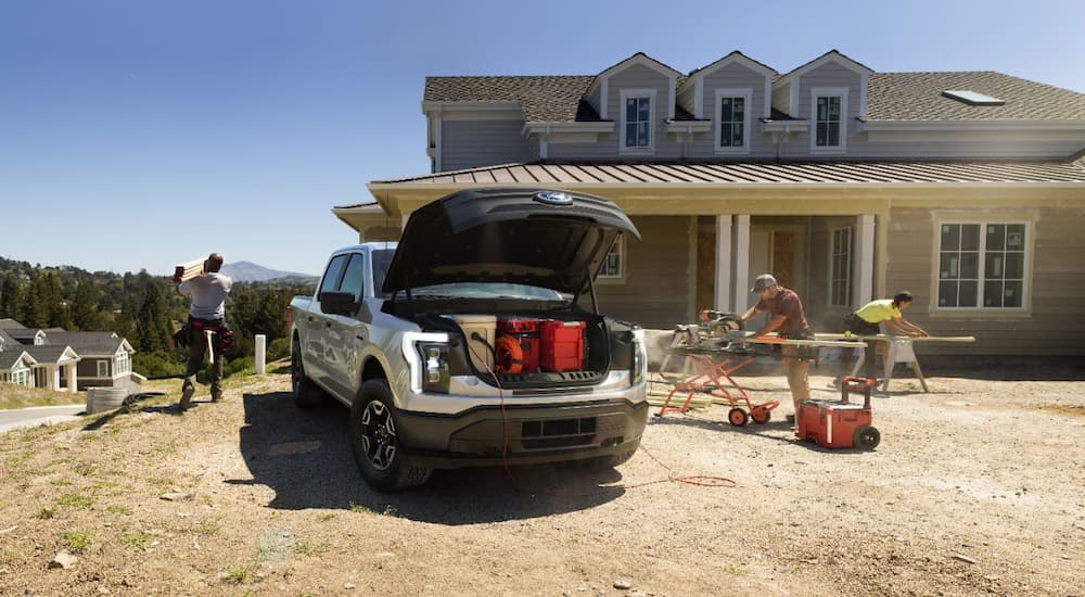 A silver 2022 Ford F-150 Lightning Pro is shown at a home construction site.
