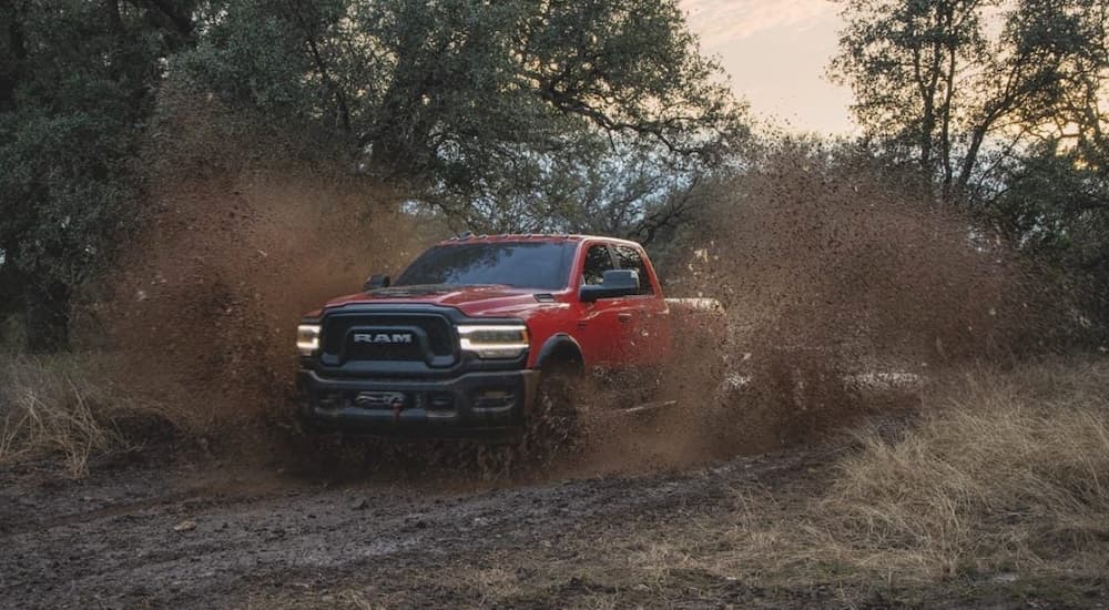 A red 2020 Ram 1500 is shown from the front driving on a dirt road.