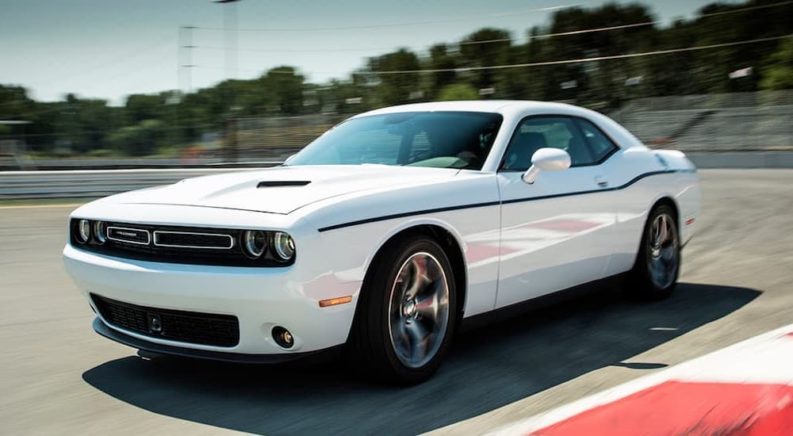 A white 2015 Dodge Challenger is shown from the side driving on a race track.