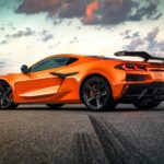 An orange 2023 Chevy Corvette Z06 is shown from the side on a cloudy day.