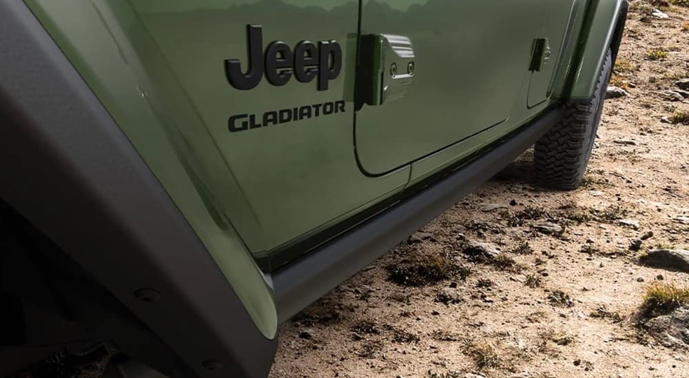 A close up of the door and Jeep badge on a green 2022 Jeep Gladiator Willys is shown.