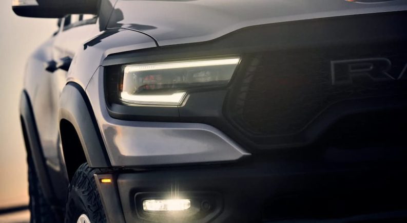 A close up of the grille and headlights of a silver 2022 Ram 1500 TRX is shown.