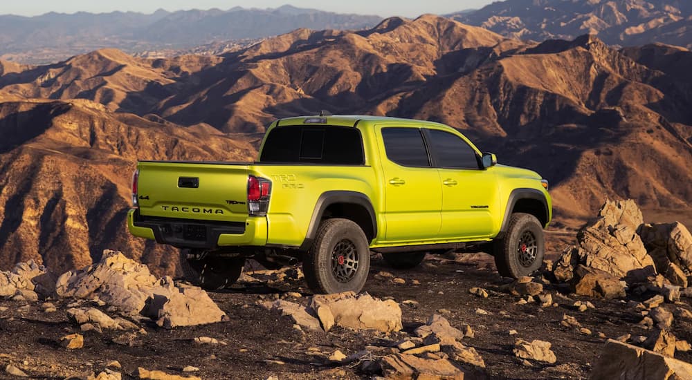 A bright green 2022 Toyota Tacoma TRD Pro is shown from a rear angle parked on a rocky mountain trail.