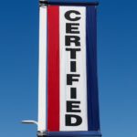 A red and blue sign reads 'certified' at a certified pre-owned Chevy dealer.