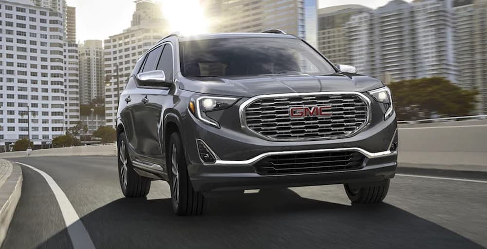 A grey 2020 GMC Terrain Denali is shown from the front driving on a city street.