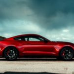A red 2020 Ford Mustang Shelby GT 500 is shown from the side parked under a cloudy sky after leaving a used Ford dealer.