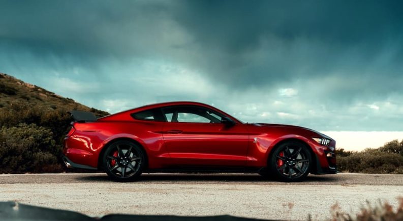 A red 2020 Ford Mustang Shelby GT 500 is shown from the side parked under a cloudy sky after leaving a used Ford dealer.