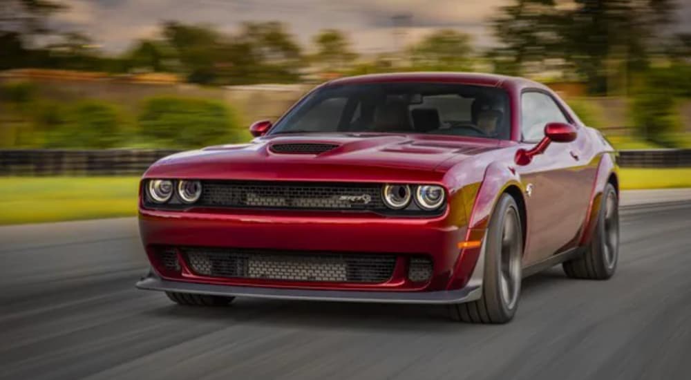 A red 2018 Dodge Challenger Hellcat widebody is shown from the front driving down the road.