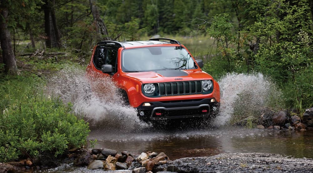 A red 2022 Jeep Renegade is shown from the front while it goes through mud.