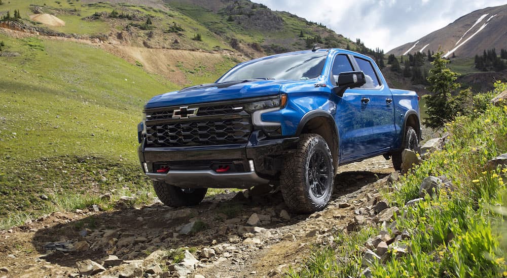 A blue 2022 Chevy Silverado 1500 ZR2 is shown from the front at an angle as it goes down a rocky trail.