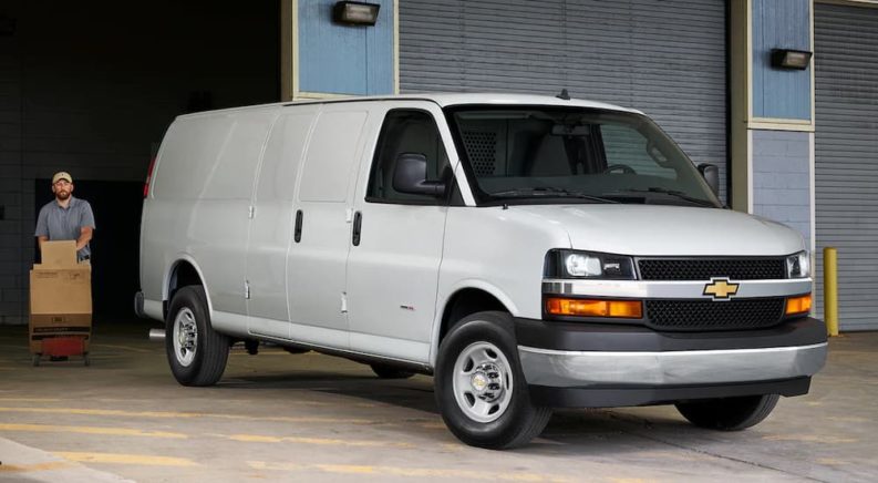 A white 2022 Chevy Express Van is shown parked outside of a loading dock.