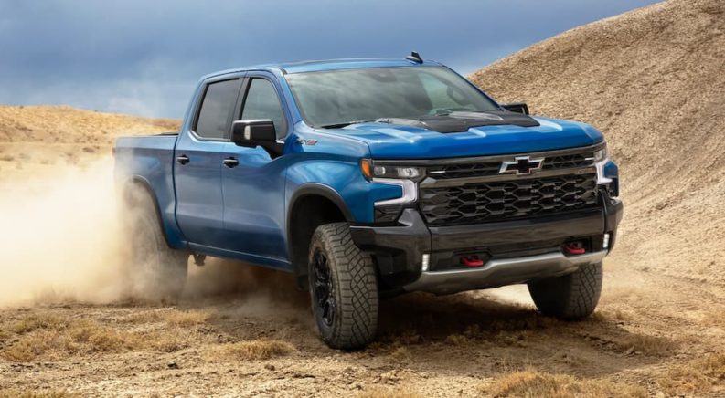 A blue 2022 Chevy Silverado 1500 ZR2 is shown from the front off-roading in a desert.