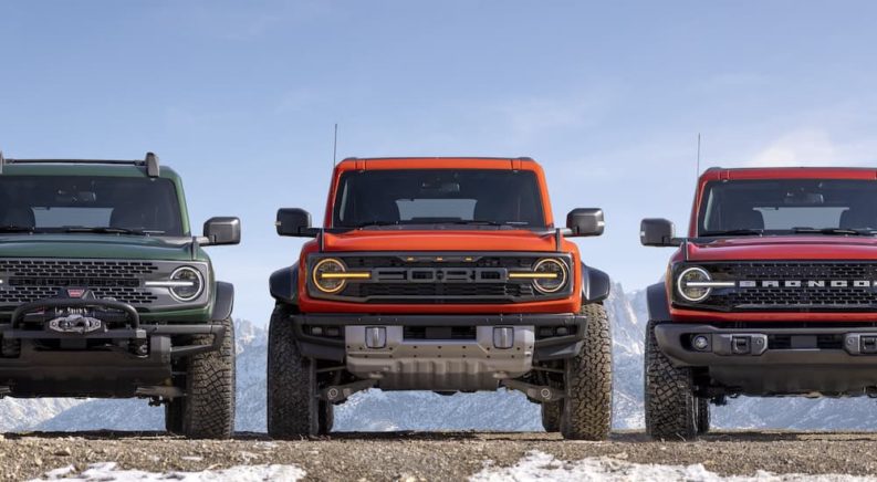 Three 2022 Ford Broncos are shown from the front in the mountains after leaving a Ford dealer.
