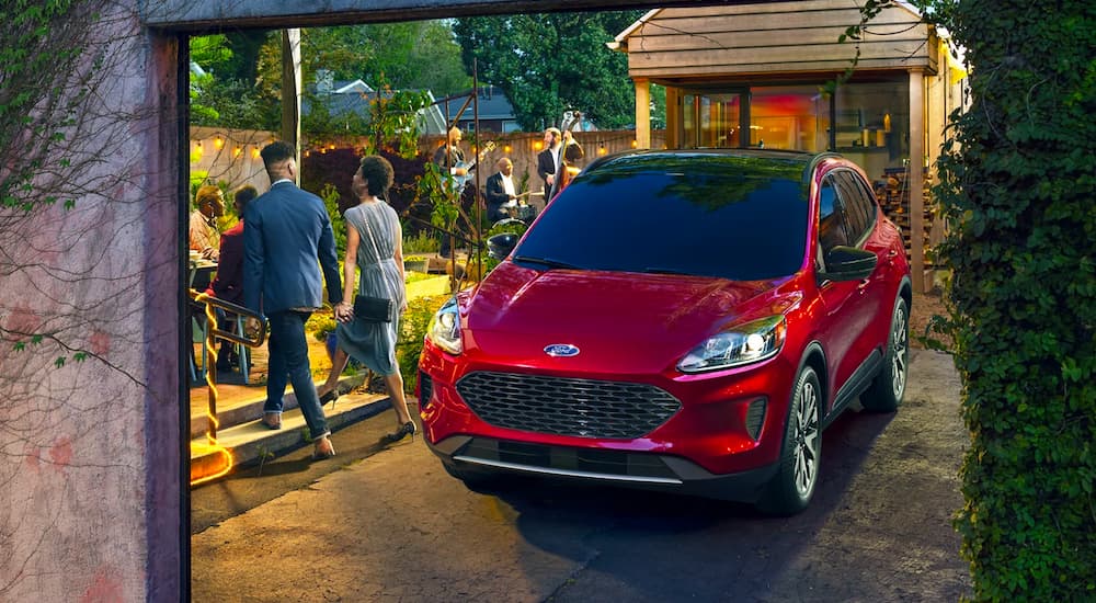 A red 2022 Ford Escape SE Hybrid is shown in a driveway next to a gathering.