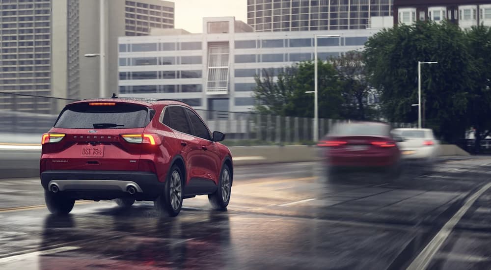 A red 2022 Ford Escape is shown from the rear driving on a city road.