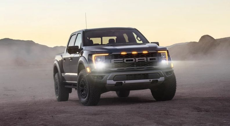 A black 2022 Ford F-150 Raptor is shown parked in a desert.