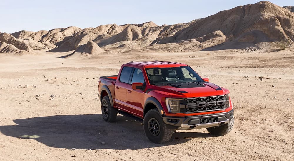 A red 2022 Ford F-150 Raptor is shown parked in an open desert area.
