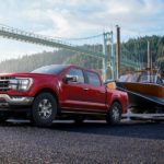 A red 2022 Ford F-150 Lariat is shown towing a boat out of a body of water.
