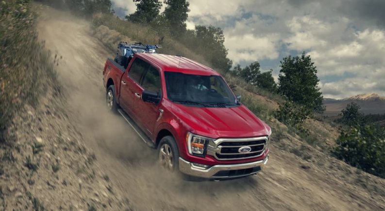 A red 2022 Ford F-150 is shown from the front driving down a steep dirt road after winning a 2022 Ford F-150 vs 2022 Toyota Tundra comparison.