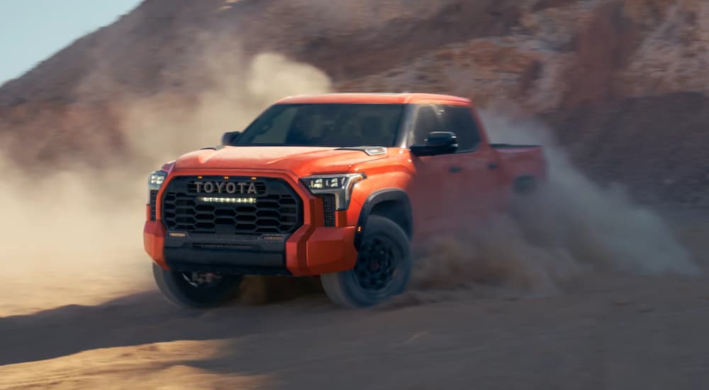 An orange 2022 Toyota Tundra TRD Pro is shown from the front off-roading in a desert.
