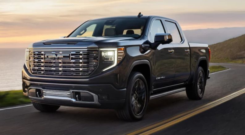 A black 2022 GMC Sierra 1500 is shown from the front driving on an open road.