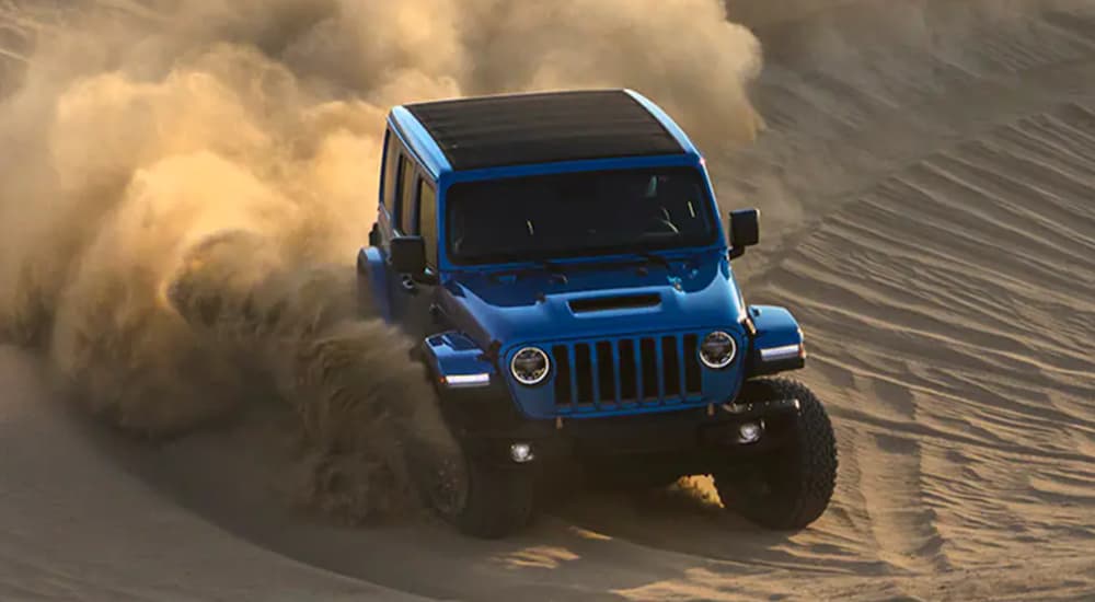 A blue 2022 Jeep Wrangler Rubicon 392 is shown from the front off-roading in a desert.