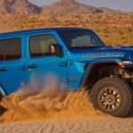 A blue 2022 Jeep Wrangler Rubicon 392 is shown from the side off-roading in a desert.