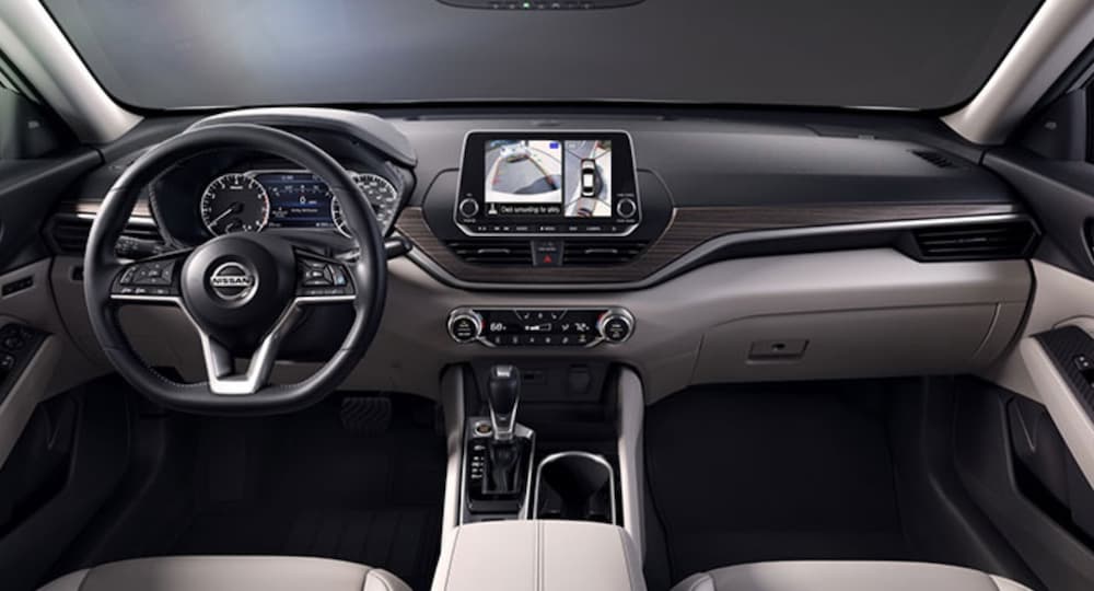 The grey and black interior of a 2022 Nissan Altima shows the steering wheel and center console.