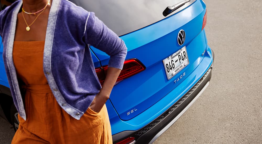 A woman is shown walking by a blue 2022 Volkswagen Taos.